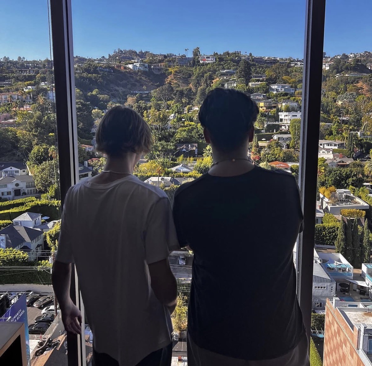 Two people looking out over a hillside city view from a high-rise window