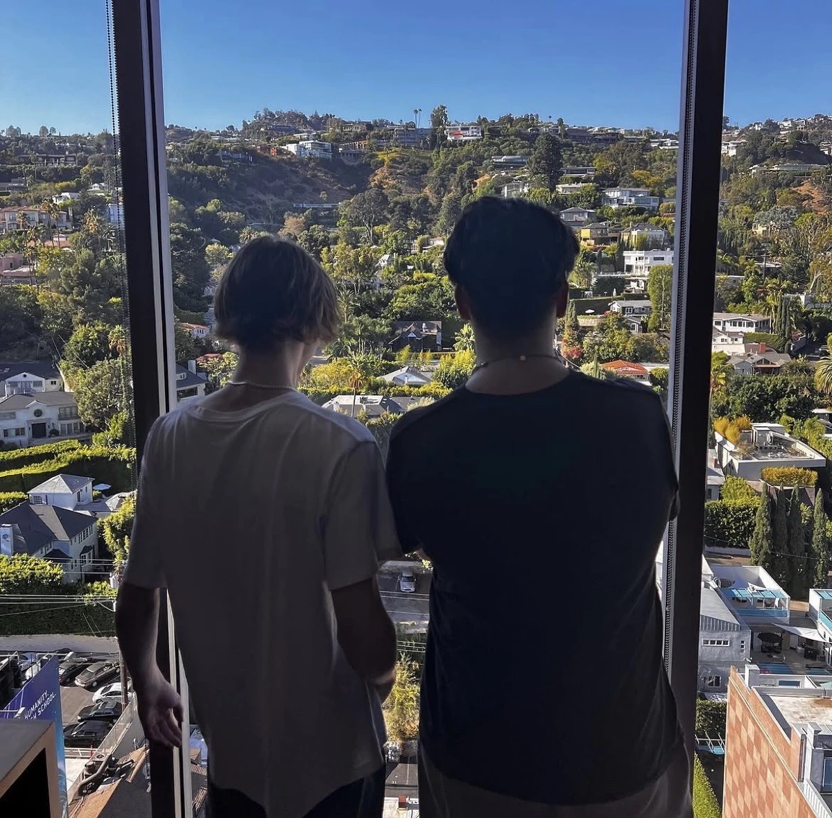 Two people looking out over a hillside city view from a high-rise window